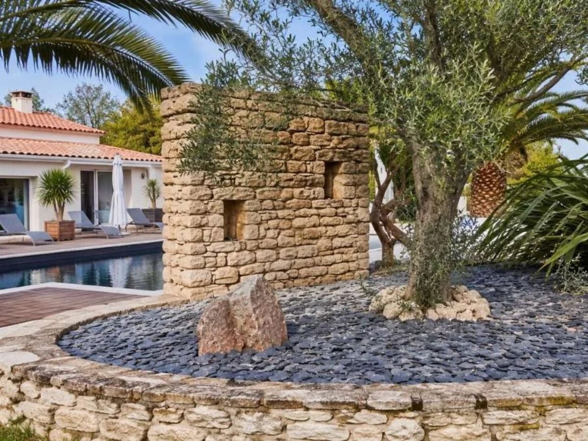 Muret décoratif en pierre naturelle et jardin minéral autour d'une terrasse de piscine réalisé en Vendée par LMA Savoir-Faire.